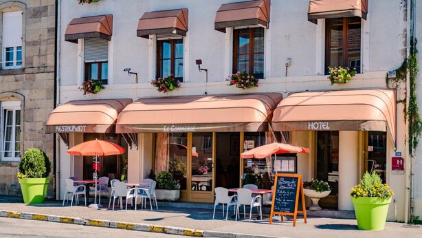 A hotel with outdoor seating, a signboard, and flower boxes. - Hotel Le Commerce (Dompaire)