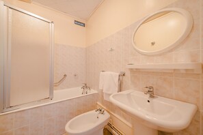 A bathroom with a shower, a sink, a bidet, and a mirror. - Hotel Le Commerce (Dompaire)