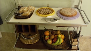 A food cart with various baked goods, a fruit basket, and a knife. - New structure in a quiet and convenient location for visiting Umbria and the surrounding area. (Amelia)