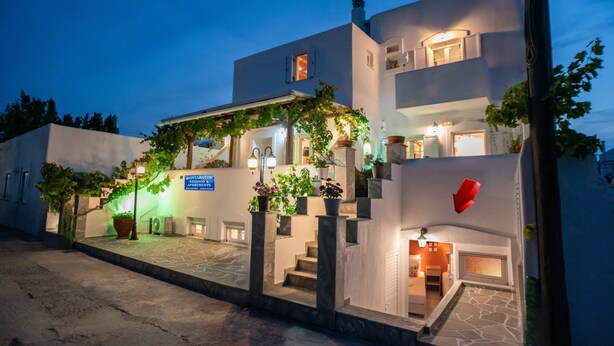 A modern building with a staircase, potted plants, and a sign indicating it is an apartment complex. - Two-Bedroom Apartment (5-6 Adults) Semi Basement, near center. (PARIKIA PAROS GREECE)