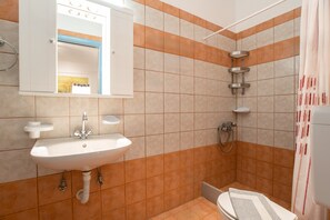 Een bad/douchecombinatie, een haardroger, handdoeken, shampoo