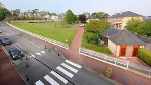 A street view with a pedestrian crossing, a grassy area, and a building with a sign. - Villa Sandret by Interhome (Villers sur mer)