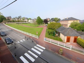 Vista da rua com faixa de pedestres, gramado e um edifício com placa.