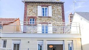 A two-story building with a stone facade, a balcony, and a ground-level entrance with a blue door. - Villa Sandret by Interhome (Villers sur mer)