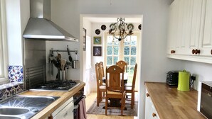 Cuina amb forns, rentatols i armaris de fusta. Hi ha una taula de menjador amb cadires i un penjallum.