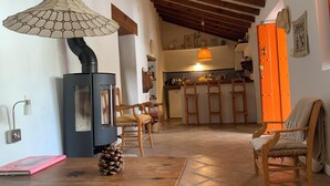 Uma sala de estar aconchegante com lareira, móveis de madeira e uma área de cozinha ao fundo.