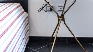 A small, round table with a red lamp on top, positioned next to a bed with a patterned bedspread. - Beautiful furnished apartment in the center (int. 1) (brindisi)