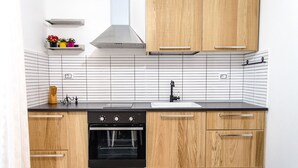 A modern kitchen with wooden cabinets, a black oven, and a white tiled backsplash. - Beautiful furnished apartment in the center (int. 1) (brindisi)