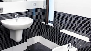 A modern bathroom with a white sink, bidet, and toilet, black tiled walls, and a window. - Beautiful furnished apartment in the center (int. 1) (brindisi)