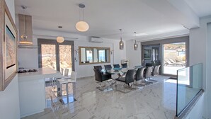 Una cocina moderna con zona de comedor de vidrio, ventanas amplias y vistas al exterior.