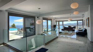 Una sala de estar moderna con barandilla de vidrio, una mesa de comedor de cristal y un sofá.