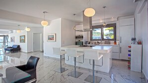 Una cocina moderna con una isla central, taburetes de bar e iluminación colgante.