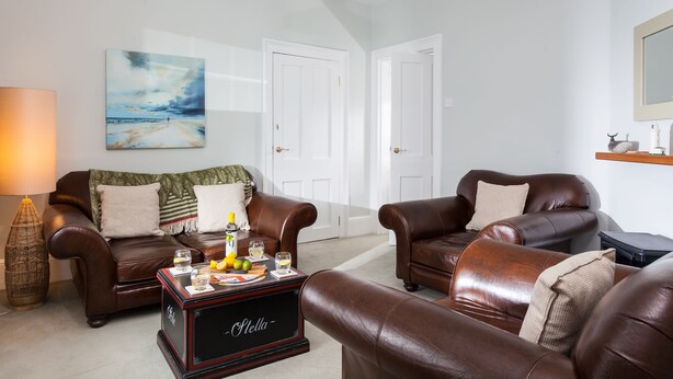 A living room with two leather sofas, a coffee table, a painting, and a door.