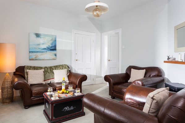 A living room with two leather sofas, a coffee table, a painting, and a door.