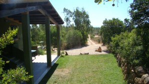 A covered patio area with a stone wall and a grassy lawn.