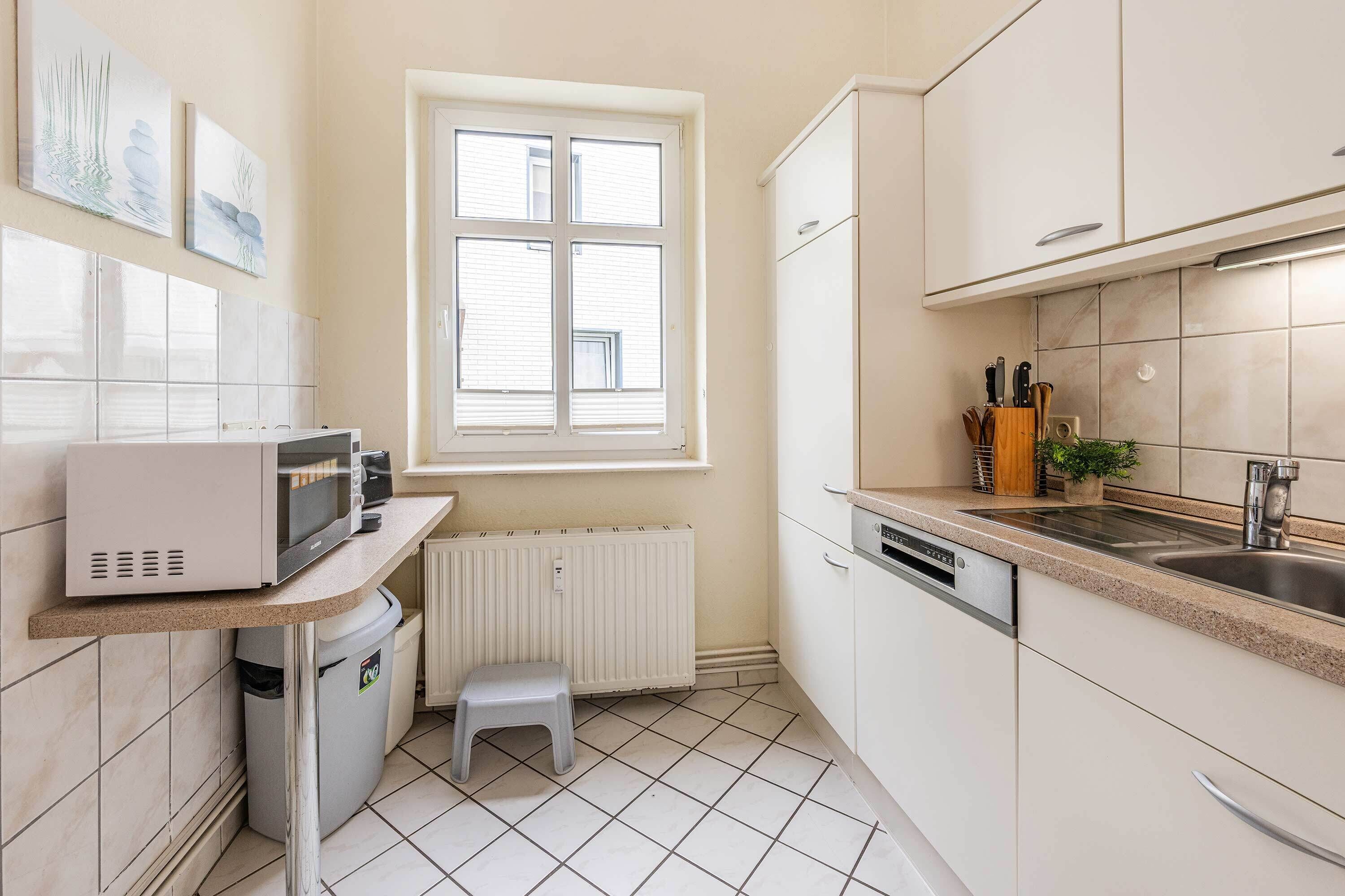 Een kleine keuken met een magnetron, spoelbak en kastjes.
