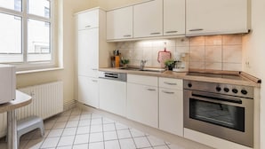 Una cocina moderna con armarios blancos, horno empotrado, pileta y ventana.