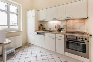 A modern kitchen with white cabinets, a built-in oven, a sink, and a window.