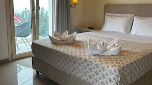 Una habitación de hotel con una cama, una mesita de noche, una lámpara y vistas a través de un ventanal corredero.