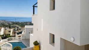 Un edificio blanco con piscina, una maceta amarilla y vistas al mar y a la ciudad.