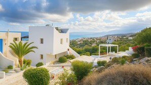 Un edificio moderno blanco con techo plano, un pequeño balcón y vistas a un pueblo costero.