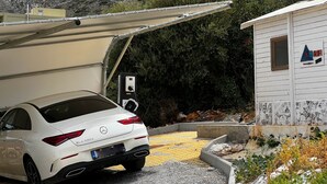 Un Mercedes-Benz CLA 250 blanco estacionado en un área de estacionamiento techada con una estación de carga cerca.