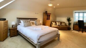A bedroom with a bed, bedside table, dresser, and a window.