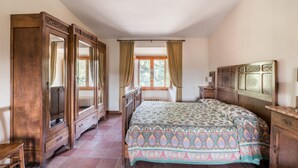 Ein Schlafzimmer mit einem großen Bett, einem Holzschrank und einem Fenster mit Vorhängen.