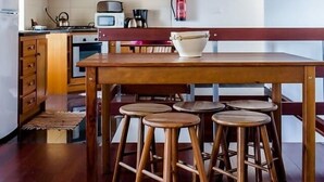 A kitchen with wooden beams, a wooden table, and four stools. - Casa da Avó - Quinta da Ribeira da Urze (Prainha de cima)