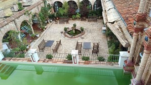 Un patio con una fuente, zonas de estar y vistas del paisaje circundante.