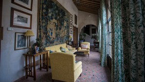 Un interior tradicional con un sofá, sillones, una mesa y un tapiz grande.