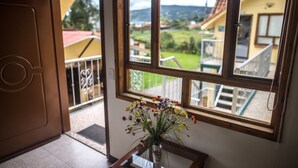 A room with a large window, a wooden door, and a vase with flowers on a table. - Hospederia El Portal de las Flores (Chia)