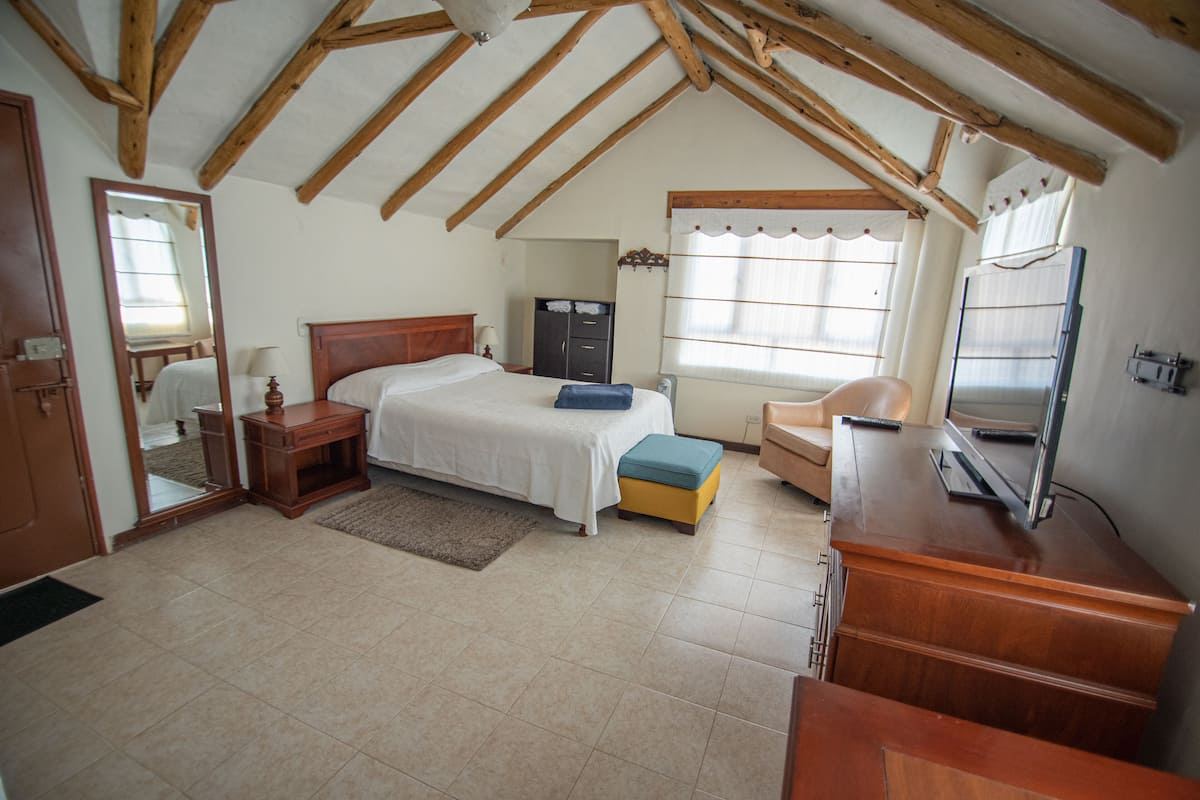 A bedroom with a bed, bedside table, dresser, and a television.