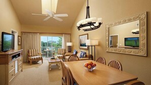 A dining and living area with a large table, chairs, a television, and a ceiling fan.