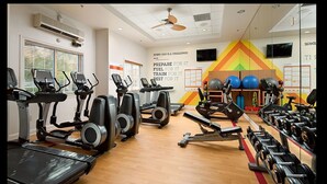 Een fitnessruimte met loopbanden, elliptische trainers en halterbanken.