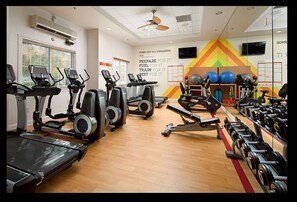 Een fitnessruimte met loopbanden, elliptische trainers en halterbanken.