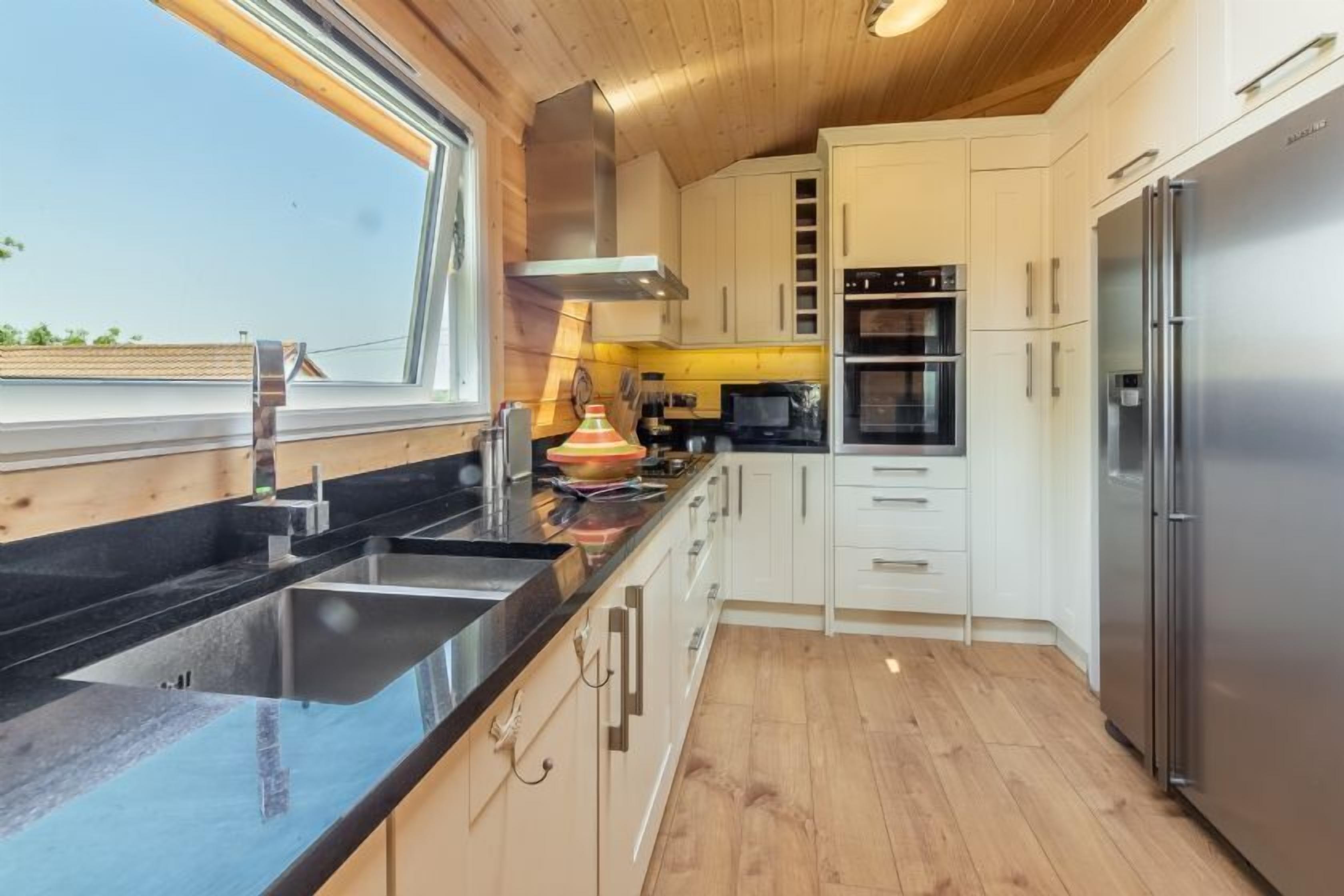 Una cocina moderna con encimera negra, electrodomésticos de acero inoxidable y suelo de madera.