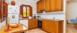 A kitchen with wooden cabinets, a white refrigerator, a microwave, and a sink. - Can Crestall 414 rustic finca with private pool, air conditioning, garden and barbecue (Campos)