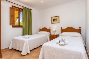 A hotel room with two beds, a window with curtains, a bedside table with a lamp, and a framed picture on the wall. - Can Crestall 414 rustic finca with private pool, air conditioning, garden and barbecue (Campos)