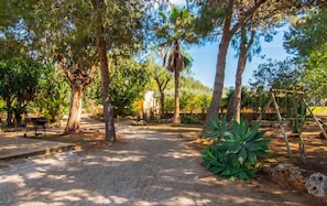A garden with trees, a barbecue area, and a swing set. - Can Crestall 414 rustic finca with private pool, air conditioning, garden and barbecue (Campos)