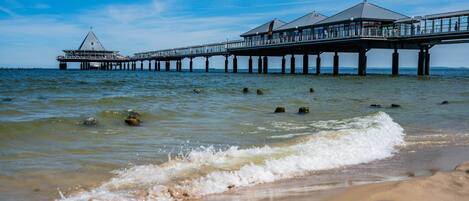 A pier extending into the water with a building at the end, supported by multiple pillars.