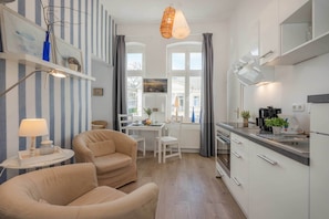 Eine moderne Küche mit weißen Schränken, einem Essbereich mit Tisch und Stühlen sowie einer Sitzecke mit zwei Sofas.