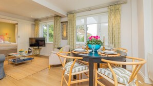 A dining area with a round table, chairs, and a TV in the background. - Marsh Lodge, Aldeburgh (Aldeburgh)
