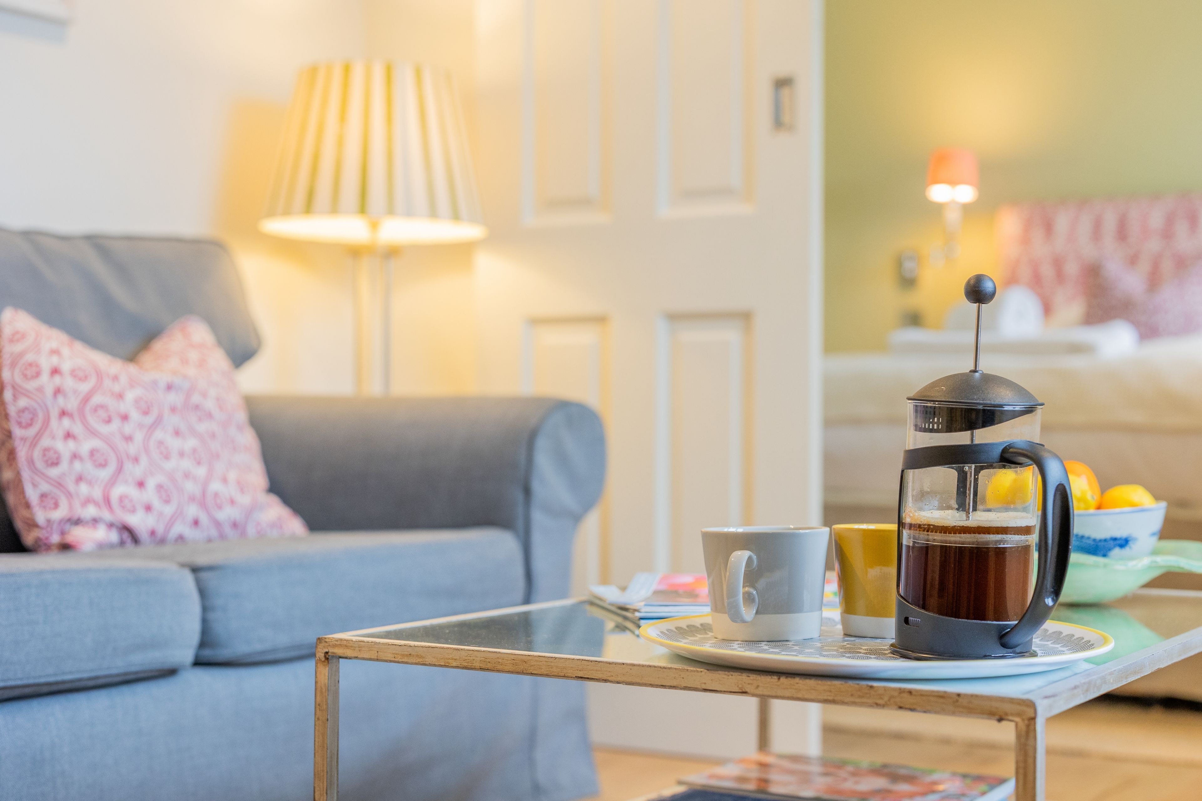 A cozy living room with a sofa, a coffee table, a coffee maker, and a cup.