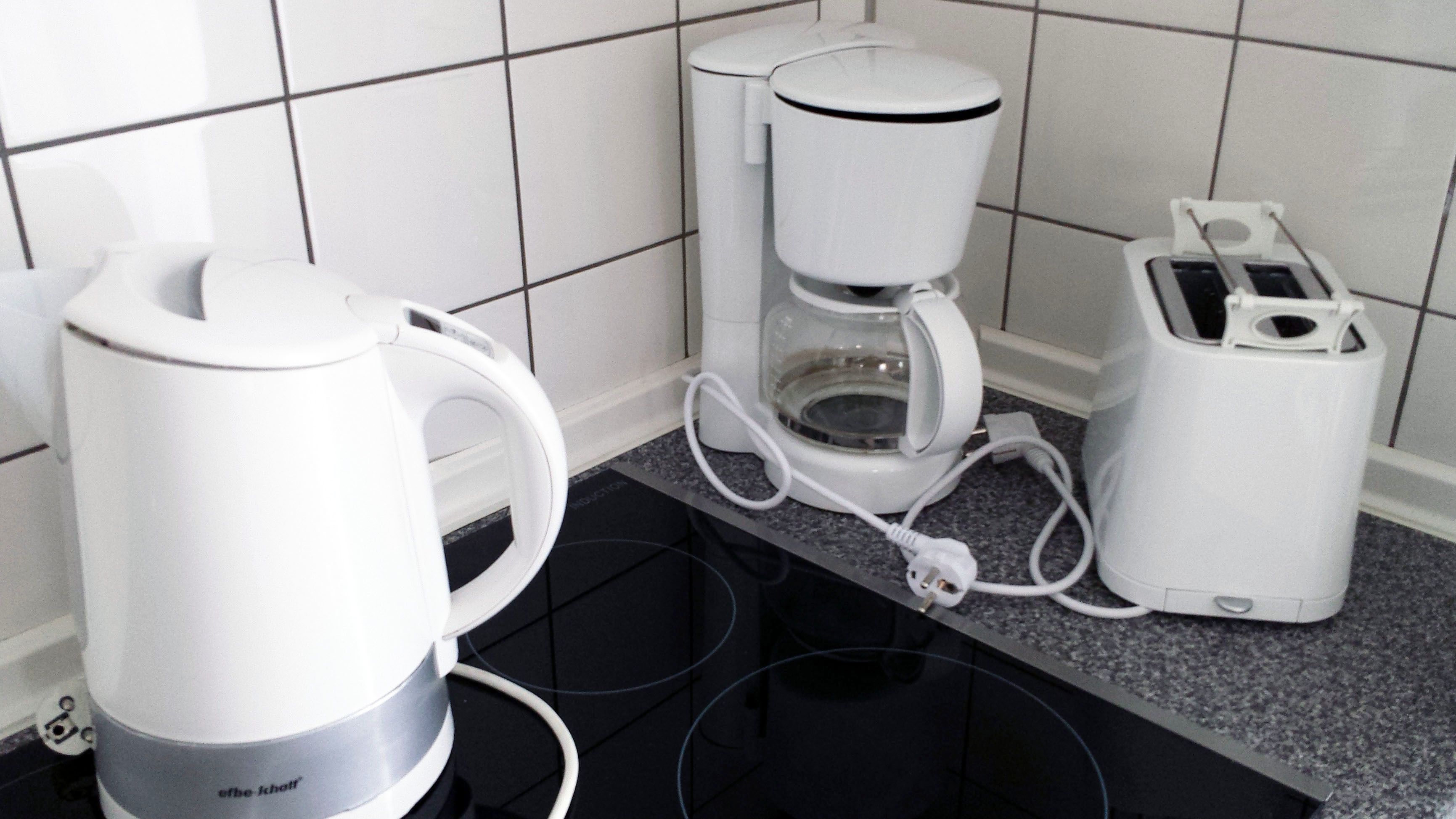 Une cuisine équipée d’une machine à café, d’un grille-pain et d’une bouilloire, le tout posé sur un plan de travail en granit.