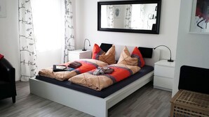 A modern bedroom with a bed, bedside tables, a mirror, and a window with curtains. - FeWo II, V und VI  - Altstadt - Am grossen Garten (Dresden)