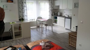 A compact, well-lit room with a kitchenette, a dining area, and a bed with a red blanket. - FeWo II, V und VI  - Altstadt - Am grossen Garten (Dresden)