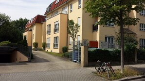A multi-story residential building with a paved entrance, a gated driveway, and a bicycle parked near the entrance. - FeWo II, V und VI  - Altstadt - Am grossen Garten (Dresden)