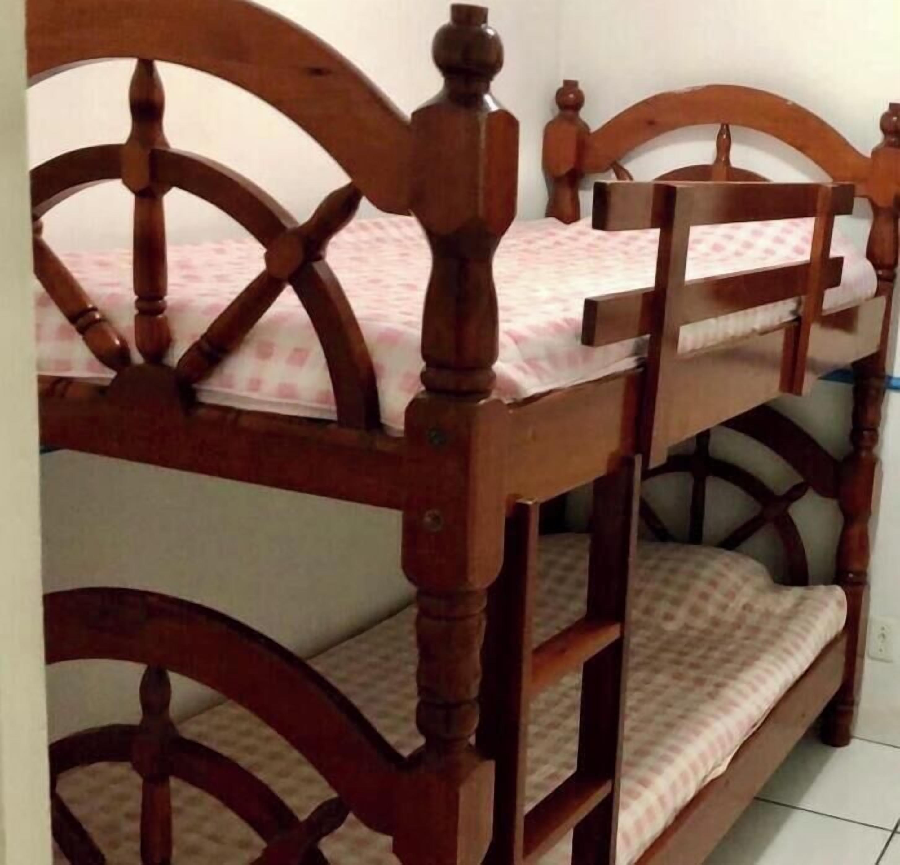 A bedroom with a wooden bunk bed and a single bed, labeled as Suite F with two single rooms.