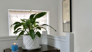 A dark wooden console table with a potted plant, a blue candle, and a wicker basket. - The Woodfarm Lodge - 3 Bedroom House (Oxford)